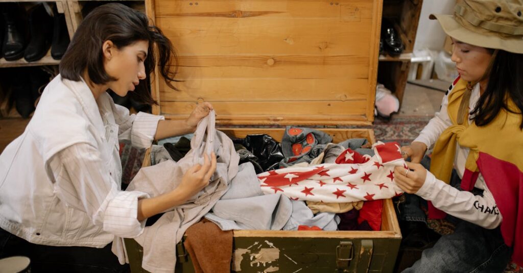 Two women sort through vintage clothes in a wooden trunk at a thrift store.